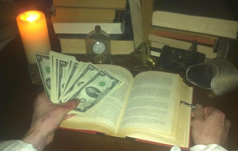 $20 bills in front of an open book and vintage items on a dark wooden table, creating a nostalgic atmosphere for Hall of Fans.