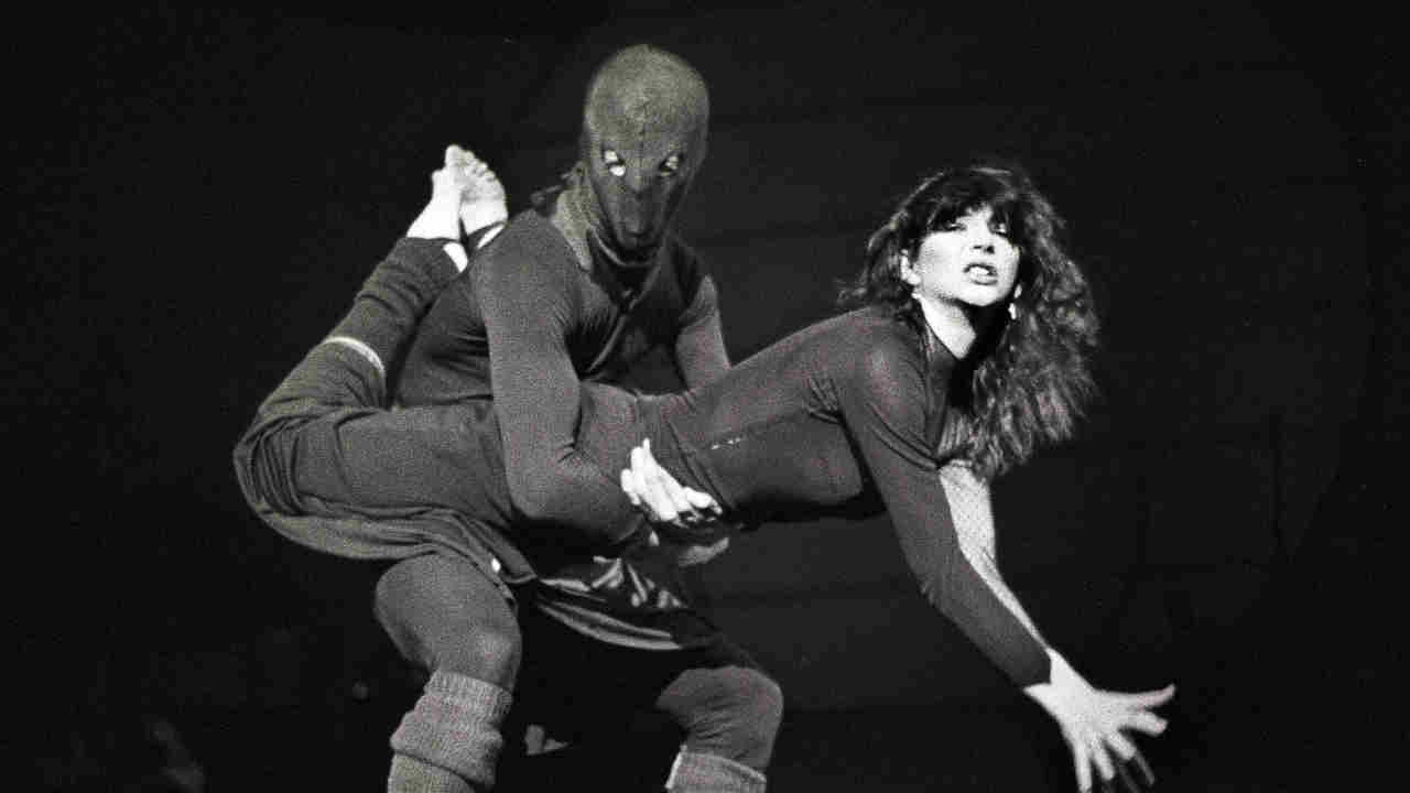 Kate Bush performing onstage with a masked dancer in 1979