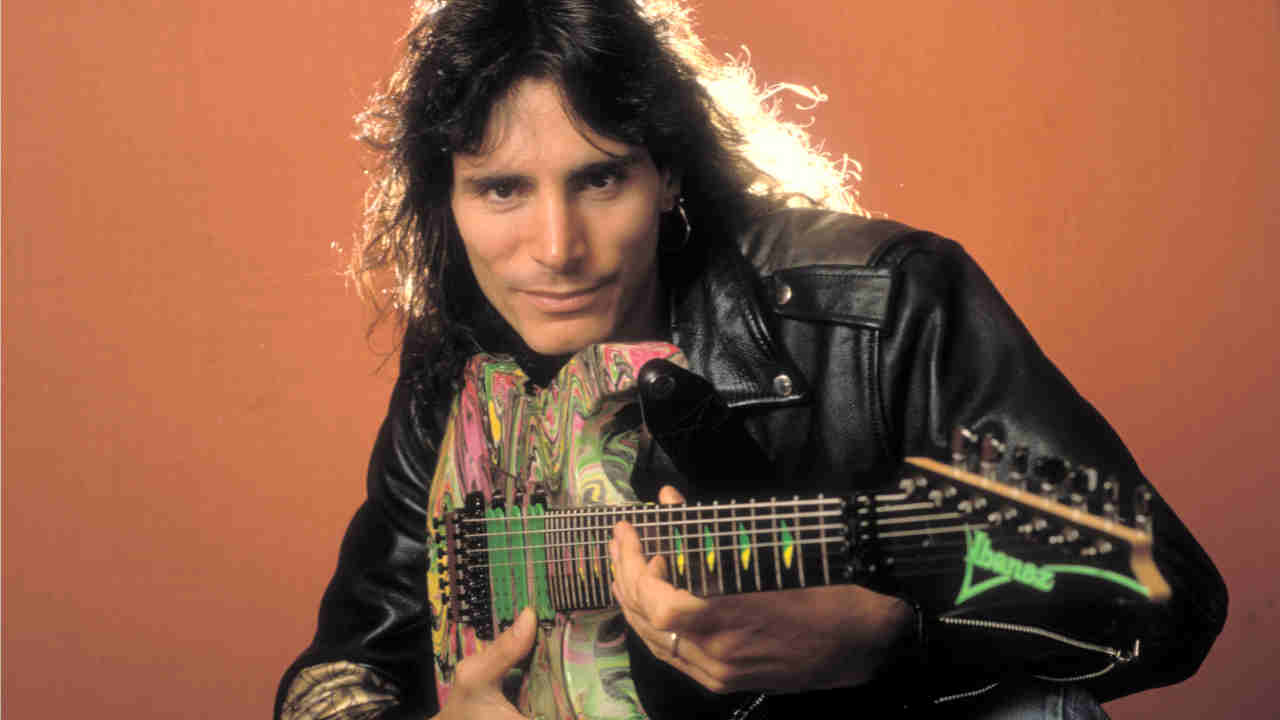 Steve Vai posing with a guitar in 1990